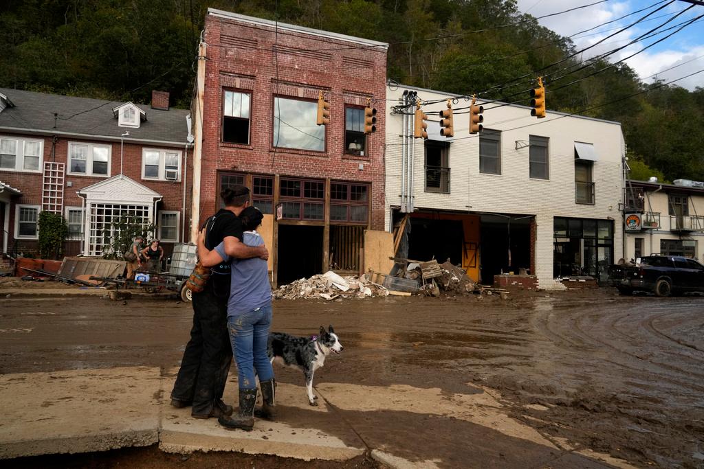 Resident Anne Schneider, right, hugs her friend Eddy Sampson as they survey damage left in the wake of Hurricane Helene in Marshall, N.C. 