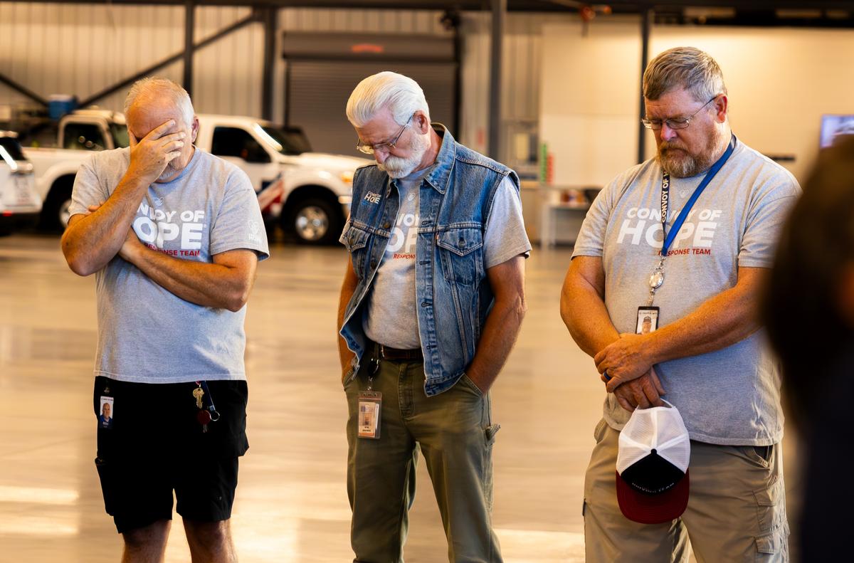 Three men bowing their heads in prayer