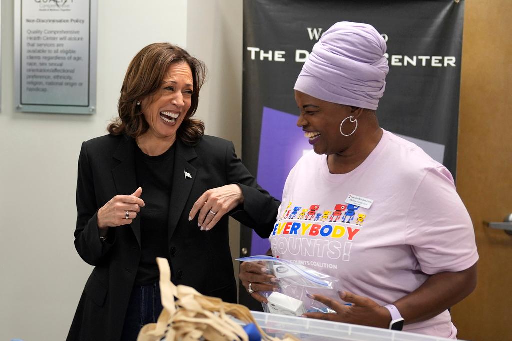 Vice President Kamala Harris, left, greets Melissa Funderburk, a worker at a food drop-off and distribution center