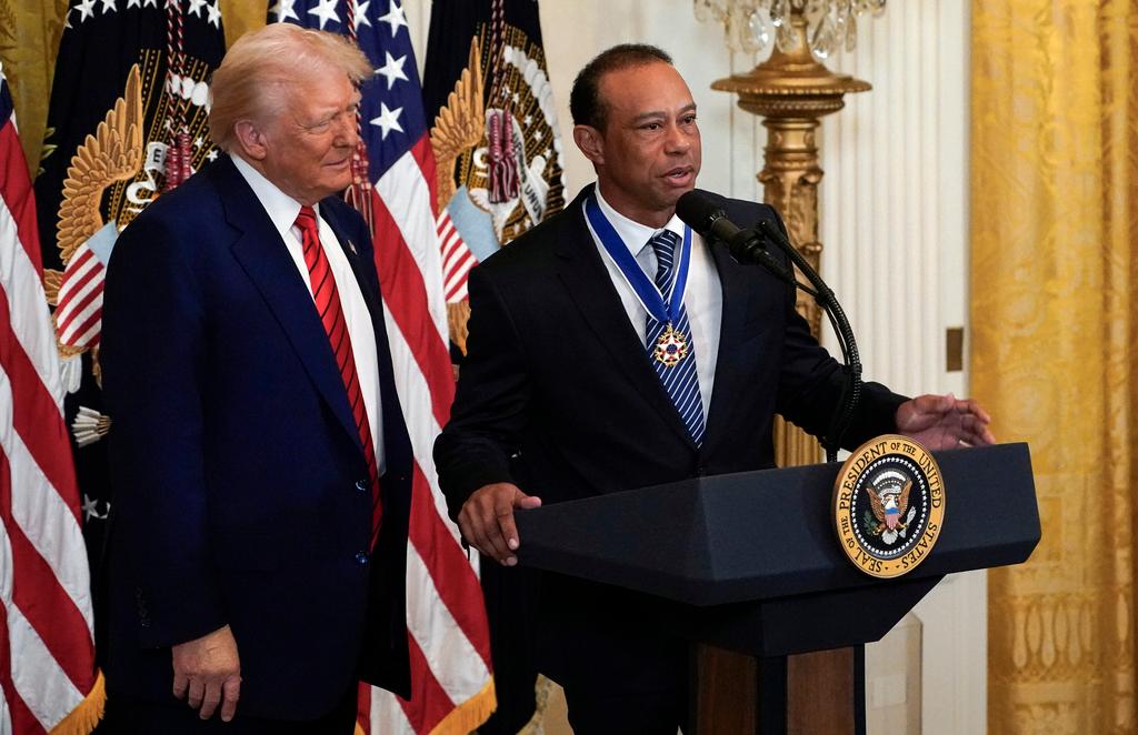 President Donald listens as Tiger Woods speaks during reception for Black History Month in the East Room of the White House